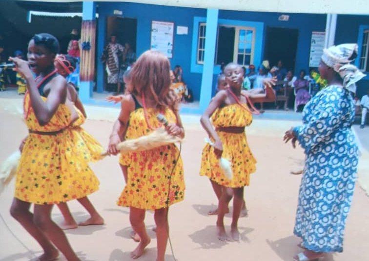 Pupils in yellow traditional outfits dancing in the school courtyard on Cultural Day